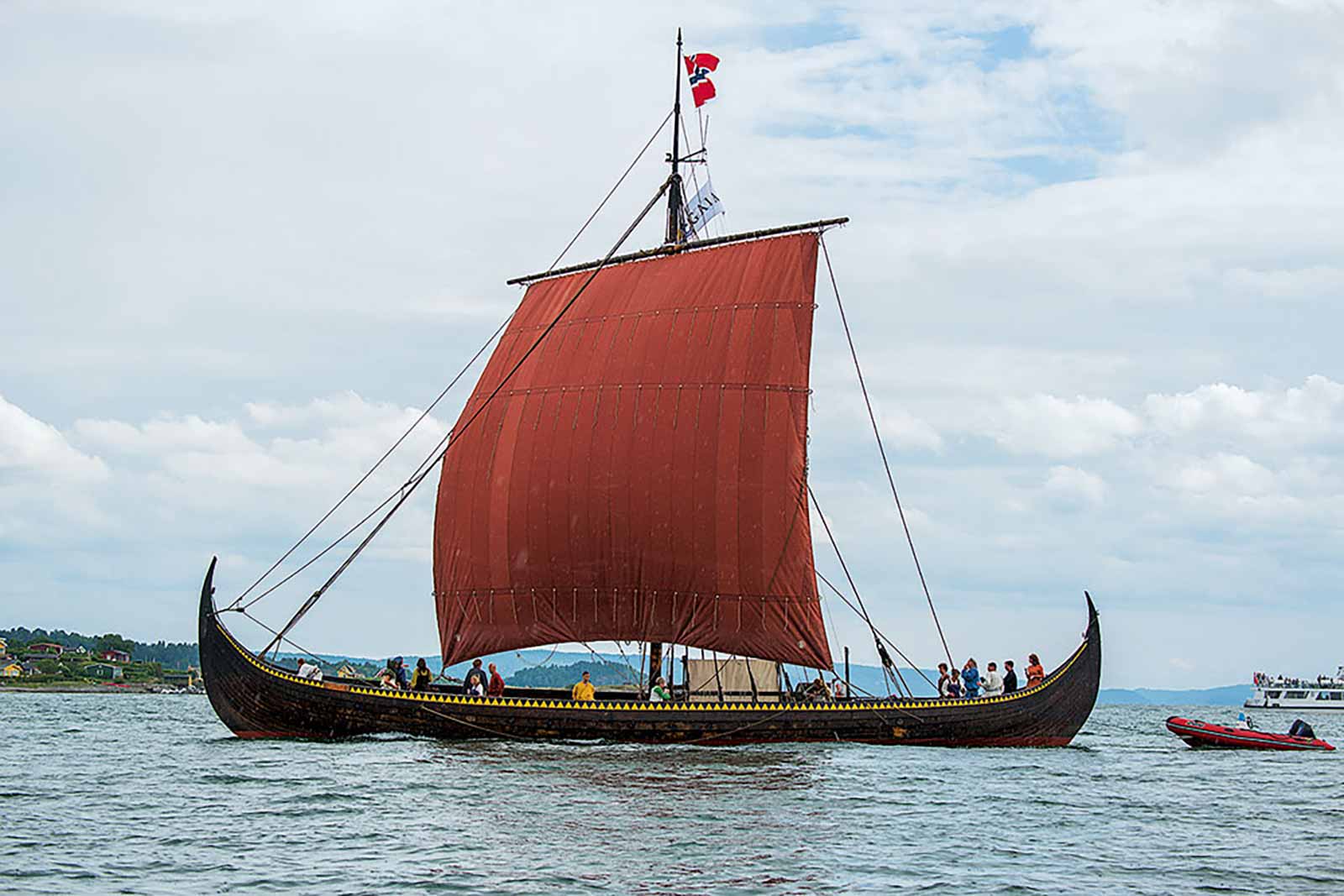 Drakkar viking Gaîa avec voile rouge, naviguant sur l'océan.