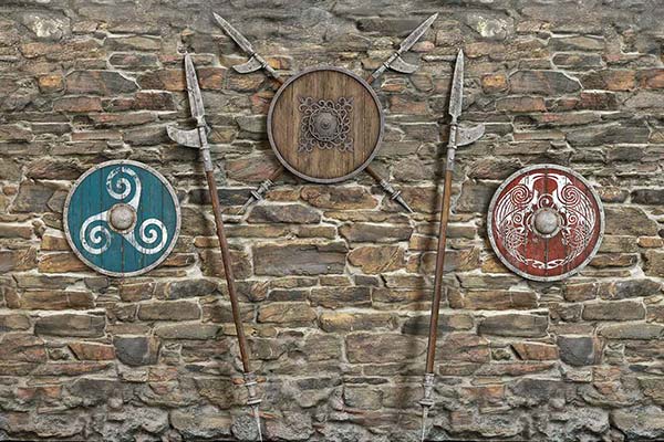 Boucliers et armes vikings sur un mur de pierre pour représenter les partenaires du drakkar de Vendée.